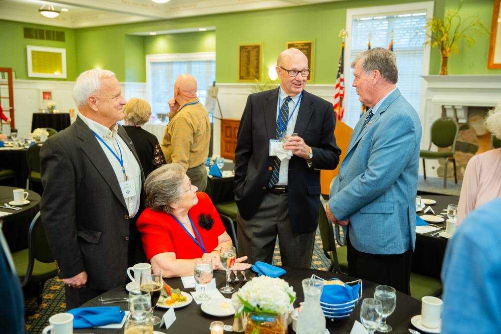 Three alumni speaking to president T-Haas at the Reunion Dinner.